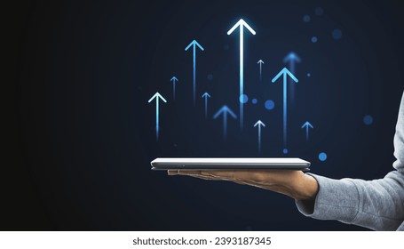Hand holding tablet with rising arrows hologram, depicting growth and digital progress concept