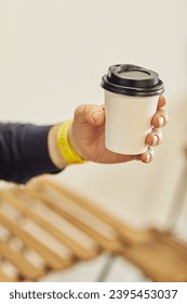 Hand holding a takeaway coffee cup with a black lid - Shutterstock ID 2395453037