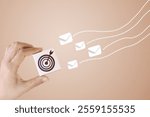 A hand holding a target icon with envelopes in motion, symbolizing targeted email marketing or communication strategies.