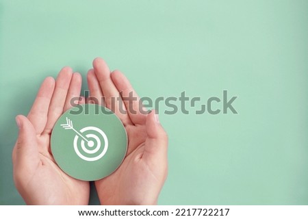 Hand holding target paper cut, achieve on point, sustianable challenge goal, business objective plan concept