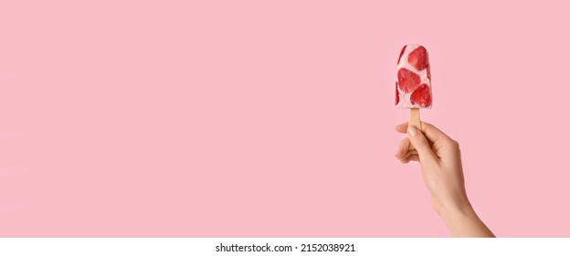 Hand holding tasty strawberry ice cream on pink background with space for text - Powered by Shutterstock