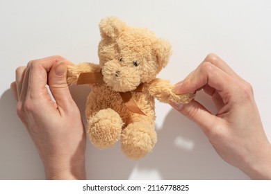Hand holding teddy bear toy isolated on white background. Concept of a friend and love. A mother holds a small brown toy bear on a palm isolated. 
