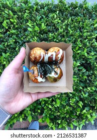 Hand Holding Thai Street Food Fish Balls Top Down Over Greenery