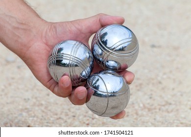 Hand is holding three Bocca balls to play Jeu de Boule, a typical French game