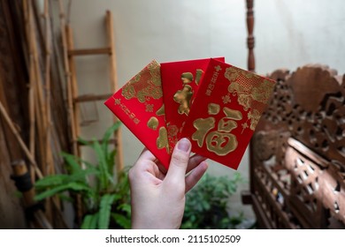 Hand holding three hong bao or ang pao. The chinese text in the envelope 