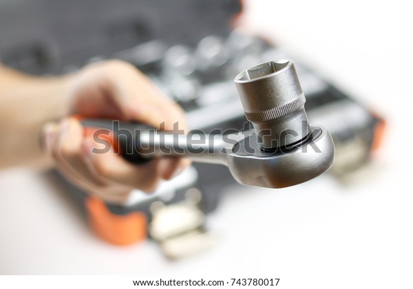 The hand holding the tool. Tool kit for the\
car. Isolated on white\
background.
