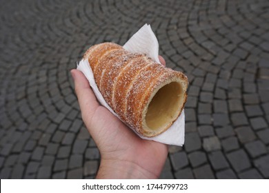 Hand holding a touristic trdelník spit cake in the streets of Prague, Czech Republic