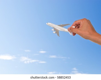 Hand Holding Toy Plane Over Blue Sky