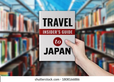 A Hand Holding A Travel Guide Book Of Visiting Japan.