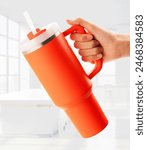 Hand holding a Tumbler With Handle over a white office, Travel Mug Straw Covers Cup with Lid Insulated Quencher Stainless Steel Water Iced Tea, Coffee.