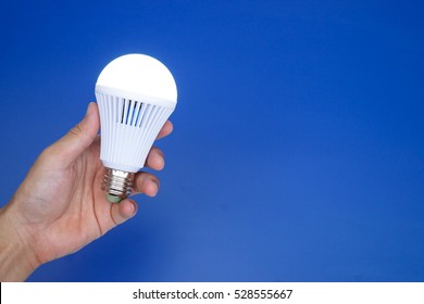 Hand holding a turned on LED light bulb / Using economical and environmentally friendly light bulb concept