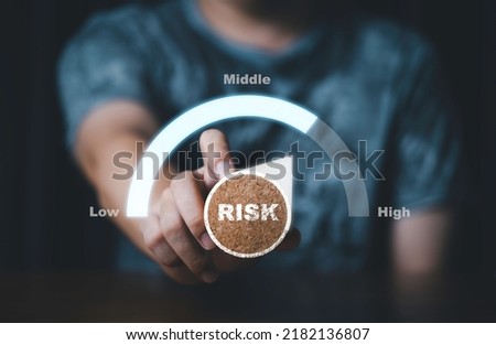 Hand holding and turning risk know from low to middle and high level meter scale from risk management analysis of business and investment concept.