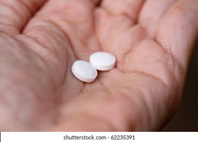 Hand Holding Two Aspirin Tablets.