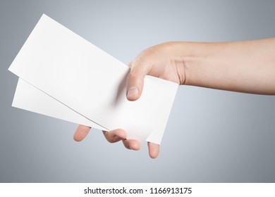 Hand holding two blank sheets of paper (tickets, flyers, invitations, coupons, banknotes, etc.), on grey background - Shutterstock ID 1166913175