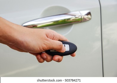 Hand holding unlock door button remote car.