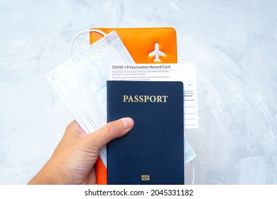 Hand holding a US passport with a vaccination record card, face mask and documents organizer in hand. International travel during covid-19. - Powered by Shutterstock