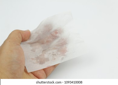 Hand holding  used blotting paper or oil removing film with the paper had oil stain on it