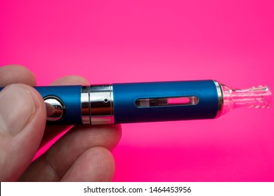 Hand Holding Vape Pen Metal Electronic Cigarette With Vaping Pink Background