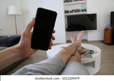 Hand holding a very modern mobile phone with a black touch screen. 