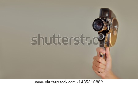 Hand holding vintage old movie camera with copy space on beige background