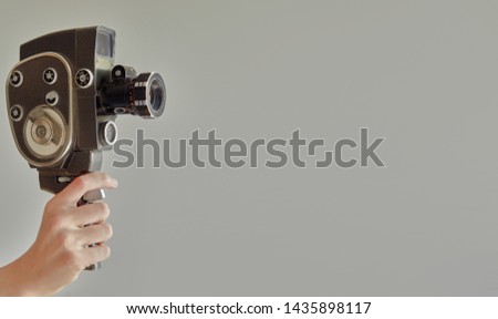 Hand holding vintage old movie camera with copy space isolated on beige background