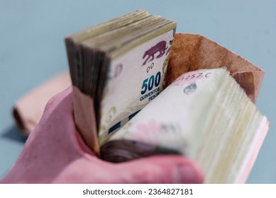 hand holding a wad of Argentine bills - Shutterstock ID 2364827181
