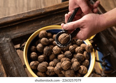 Hand holding walnuts and nutcracker and crack kemels. Deicious nuts for vegetarian heathy diet