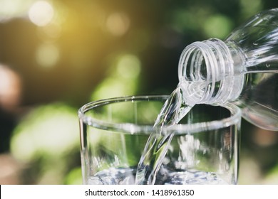 Hand holding water bottle in nature background. - Shutterstock ID 1418961350