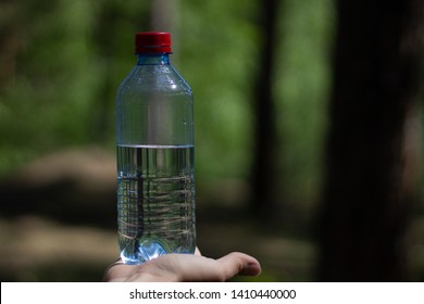 hand holding water bottle on garden background