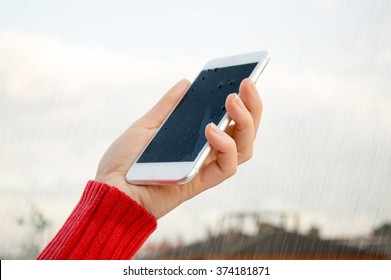 Hand Holding A Wet Smart Phone Under Rain