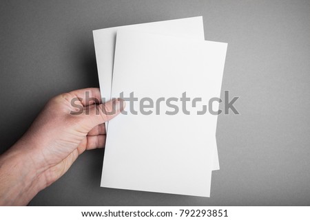 Hand holding white blank paper A5 sheet mockup. Leaflet document surface design.