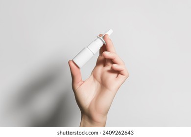 hand holding a white bottle with nasal spray