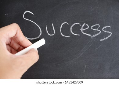 Hand holding a white chalk and Write success