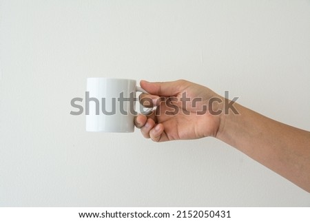 Hand holding a white cup on white background