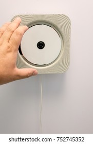 Hand Holding White Disk On Vintage CD Player Hanging On White Wall Background