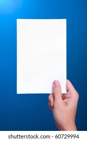 Hand Holding White Greeting Paper Card On Blue Background