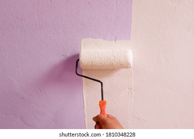 Hand Holding A White Paint Roller On The Wall