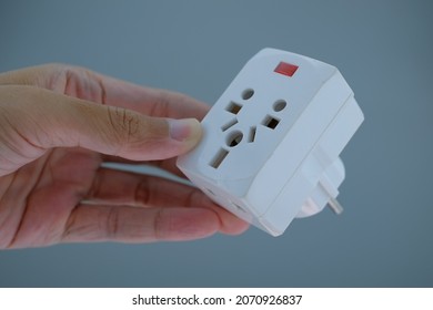 Hand holding white power plug converter. Power plug adapter isolated background. Multi plug power adapter isolated.