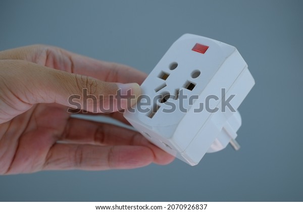 Hand\
holding white power plug converter. Power plug adapter isolated\
background. Multi plug power adapter\
isolated.