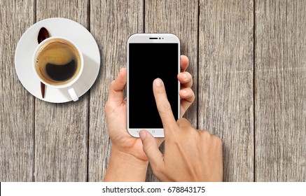 Hand holding White Smart phone on wood coffee table - Shutterstock ID 678843175