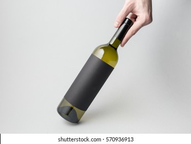 Hand Is Holding White Wine Bottle On Gray Background