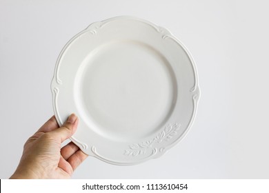 A Hand Holding White,clean And Empty,round White Porcelain Plate On The White Background.