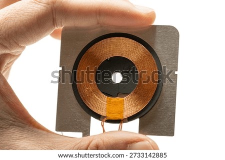 hand holding wireless charging module. usually found in wireless charger or wireless charging capable device.