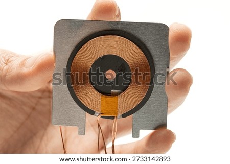 hand holding wireless charging module. usually found in wireless charger or wireless charging capable device.