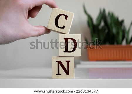 Hand holding wood cube block with 'CDN' text. CDN - short for Content delivery network