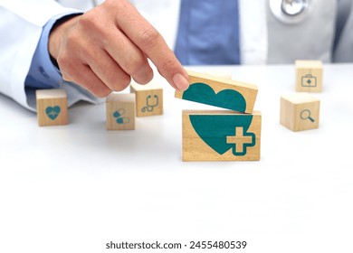 Hand holding a wooden block cube with healthcare medical symbol, heart rate icon and around is a wooden block with blurred icon symbol. Medical and health concept. - Powered by Shutterstock