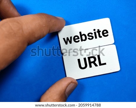 Hand holding wooden board written with text website URL on a blue background.
