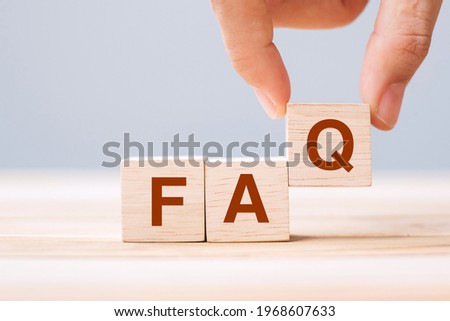 Hand holding wooden cube blocks with FAQ text (frequently asked questions) on table background. Financial, marketing and business concepts