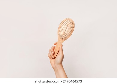 Una mano sostiene un cepillo de madera sobre un fondo liso