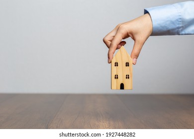 Hand holding wooden house on wooden desk,  Save money and buy house concept.